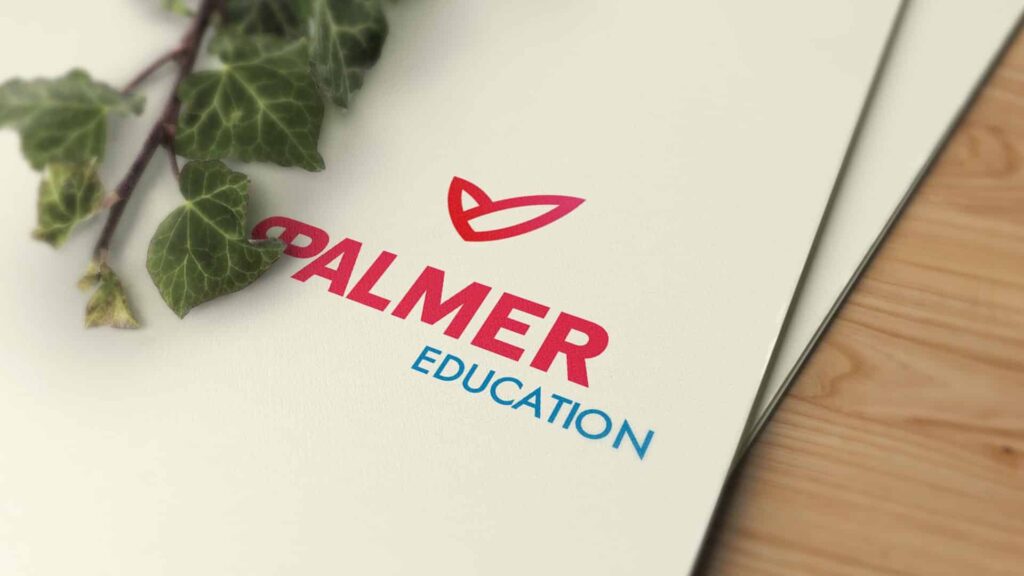 Eine Nahaufnahme einer Broschüre mit den Worten „PALMER EDUCATION“ in fetten roten und blauen Schriftarten. Über dem Text befindet sich ein einfaches rotes Emblem, das an ein offenes Buch oder einen Vogel im Flug erinnert. Auf der linken Seite der Broschüre ist teilweise eine grüne Efeuranke sichtbar.